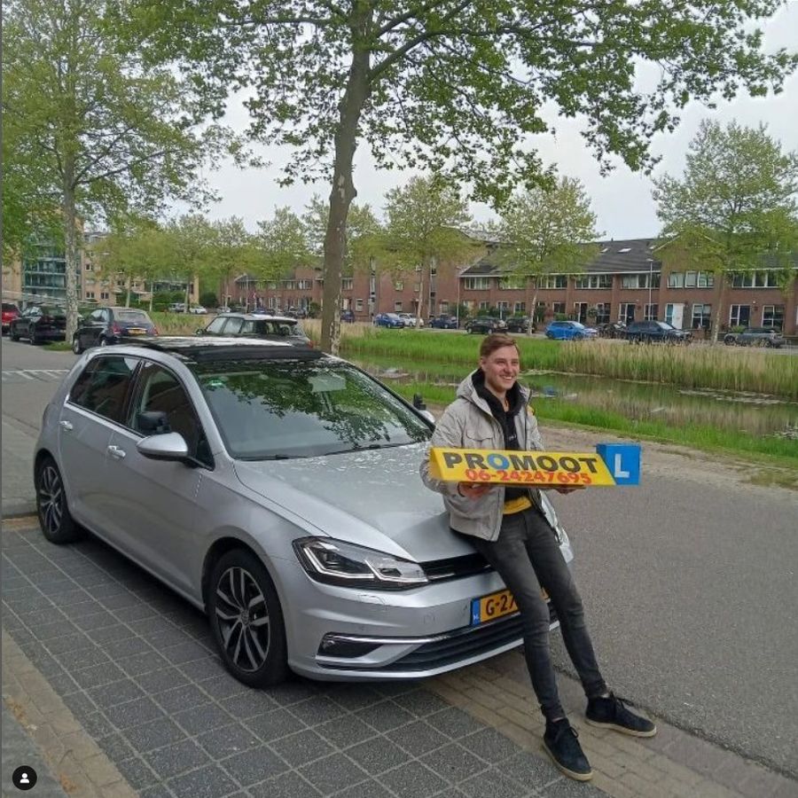 Geslaagde leerling van Autorijschool Promoot naast de zilvergrijze lesauto met het gele PROMOOT-lesbord in Ridderkerk