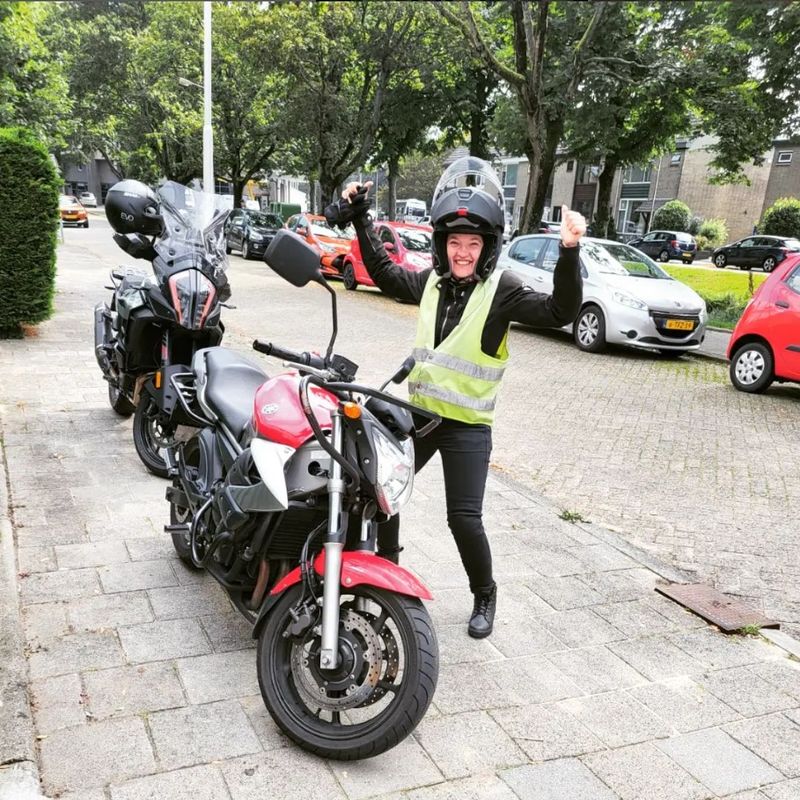 Geslaagde motorleerling juicht naast de lesmotor