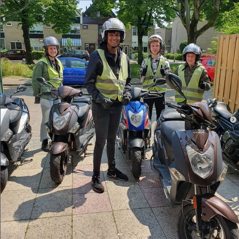 Vier leerlingen met helm naast de lesscooters tijdens een scooterdagcursus in Ridderkerk